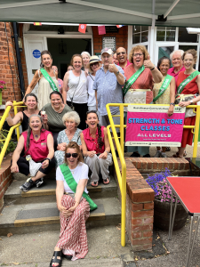 Photo of volunteers and staff standing and sitting on the entrance steps. Summer Bazaar 2025